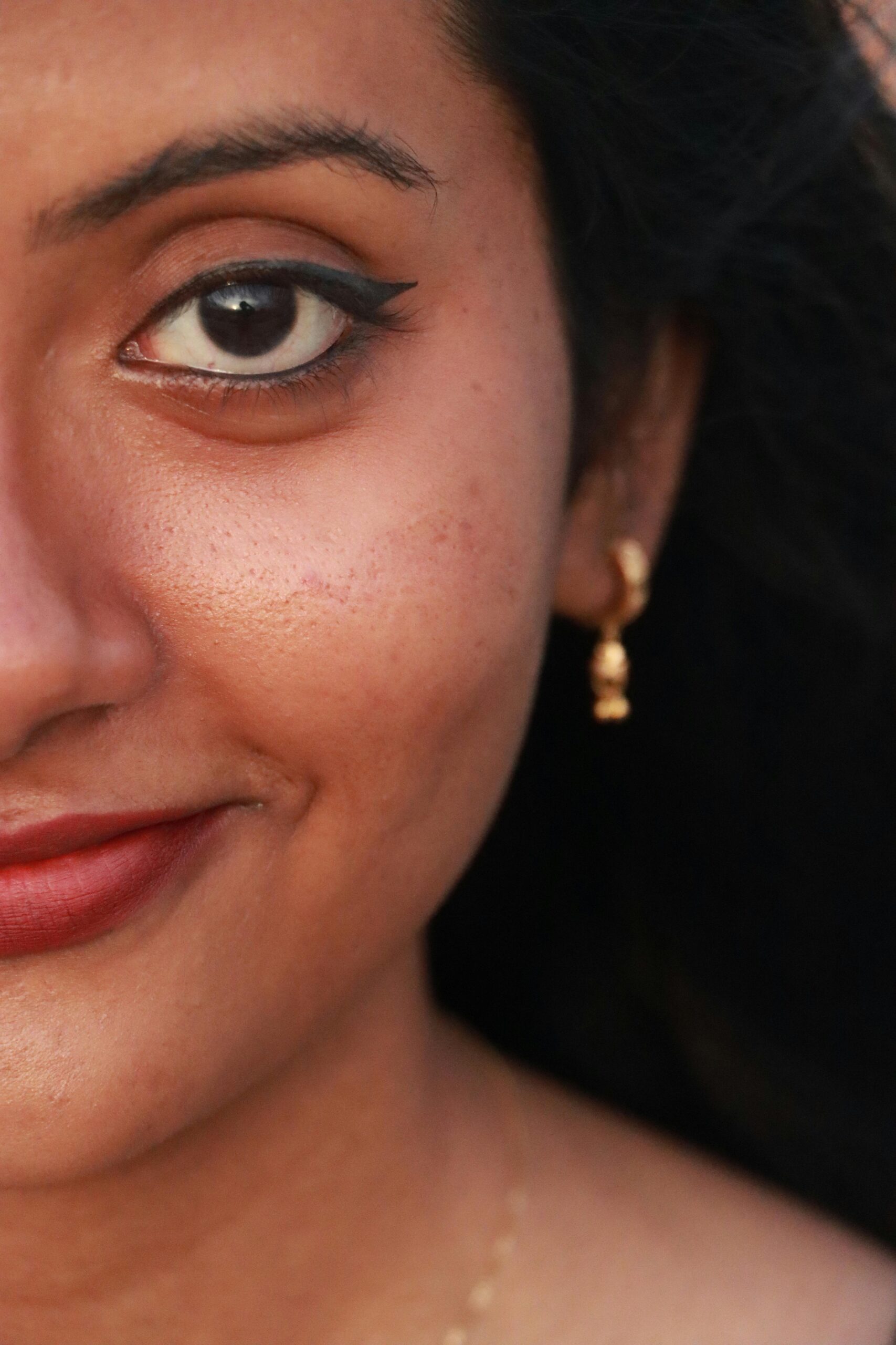 Artistic close-up portrait capturing the beauty of a smiling South Asian woman with dramatic lighting.