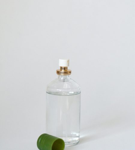 Elegant glass perfume bottle with a green cap on a light backdrop, showcasing simplicity.